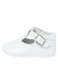 Scarpa infantile in pelle bianca con punta arrotondata, ritagli decorativi e una fascetta con fibbia laterale. Texture liscia e dettagli cuciti.