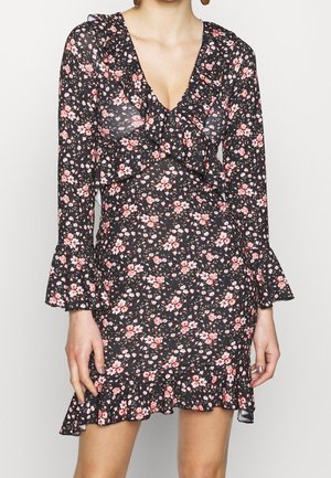 Vestido negro con flores, de mangas largas, con un escote y dobladillo con volantes, presenta flores en rosa y blanco, fabricado con un tejido ligero y transparente.