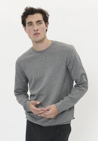 Camisa de cuello redondo de manga larga en color gris, hecha de un tejido suave y texturizado. Presenta un diseño simple con un ajuste holgado y puños acanalados.