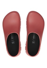 Piros, slip-on klumpák sima, gumihoz hasonló külső felülettel, lekerekített orr részsel és nyitott oldalakkal. Fekete bélés, látható méret- és márkacímkével.