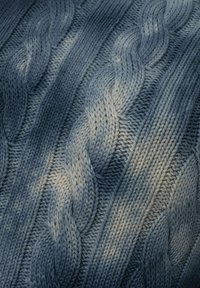 Tissu tricoté bleu avec un motif en câble, présentant des nuances allant du bleu foncé au bleu clair, mettant en valeur des textures côtelées et des motifs entrelacés.