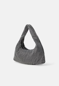 Sac à main en perles noir et blanc avec une forme douce et arrondie, présentant un design de poignée unique et une surface texturée avec des accents métalliques.