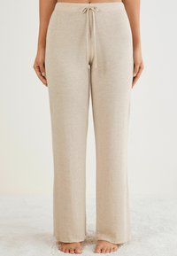 Beige loungebroeken van zachte stof, met een tailleband met trekkoord, een wijd pootontwerp en een gladde textuur voor comfort.