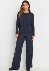 Set di abbigliamento da casa blu navy con una maglietta a maniche lunghe dalla vestibilità ampia e nodo frontale, abbinata a pantaloni a gamba larga in un morbido tessuto testurizzato.
