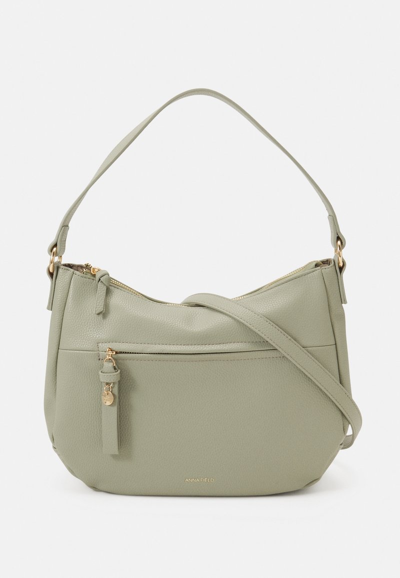 Sac à bandoulière en cuir vert clair avec poche zippée à l'avant, fermetures éclair dorées et logo embossé "ANNA FIELD" au centre en bas.