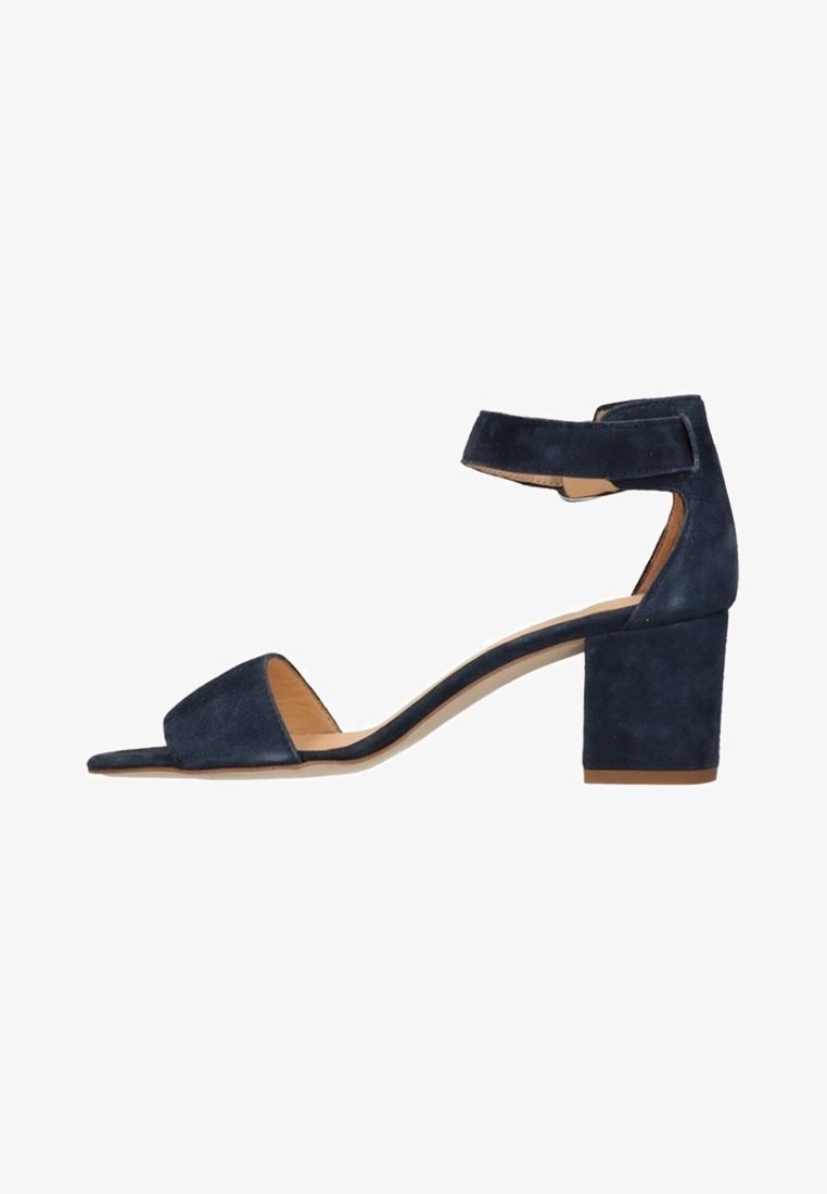 Sandale femme en daim bleu marine avec talon bloc et bride à la cheville sur fond blanc.