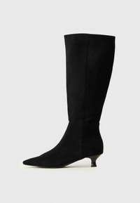 Bota de ante negra hasta la rodilla con puntera afilada y tacón pequeño. Textura suave con un diseño elegante y ajustado, con detalles de costura mínimos.