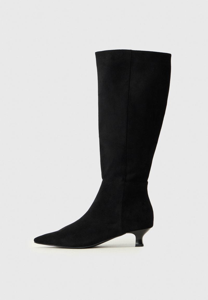 Bota de ante negra hasta la rodilla con puntera afilada y tacón pequeño. Textura suave con un diseño elegante y ajustado, con detalles de costura mínimos.