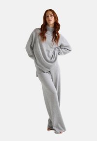 Ensemble de vêtements d'intérieur gris comprenant un col roulé ample et un pantalon à jambe large, fabriqué à partir d'un tissu doux avec une texture lisse.