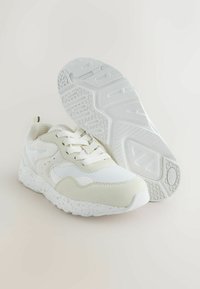 White athletic shoes with a textured mesh upper, smooth leather accents, and a speckled white sole. Features lace closure and padded tongue.