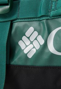 Green textured fabric with a dark bottom section. Features a white logo made of interconnected shapes, stitched strap along the top.