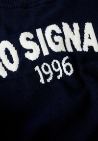 Marineblauer Strickpullover mit weißem, besticktem Text "NO SIGNA 1996". Weiche Textur, Rundhalsausschnitt und mittlere Dicke.