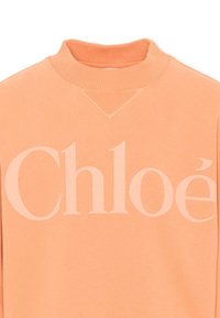 Sudadera color melocotón con cuello alto acanalado y gran logo "Chloé" en rosa claro en el pecho.