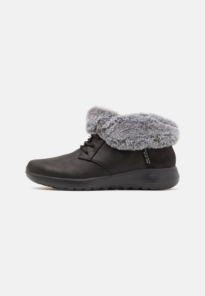 Chaussure d'hiver basse noire avec un bord en fausse fourrure grise et des lacets noirs, équipée d'une semelle en caoutchouc antidérapante pour plus de confort.