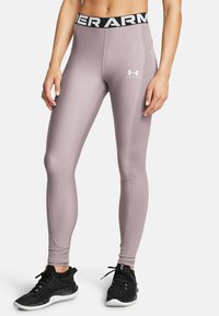 Legginsit, joiden vyötärö on korkea, vaalean violetit ja joissa on musta Under Armour -logo vyötäröllä. Sujuva, venyvä kangas, vartalonmyötäinen malli ja nilkkapituus.