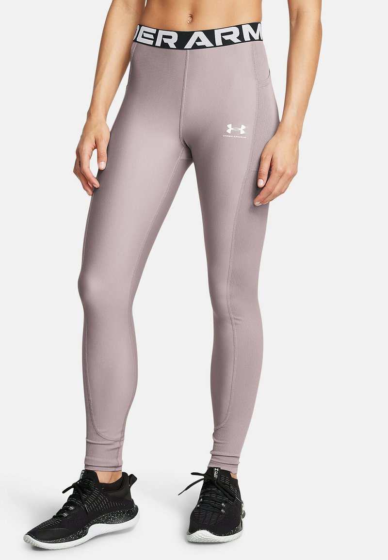 Legginsit, joiden vyötärö on korkea, vaalean violetit ja joissa on musta Under Armour -logo vyötäröllä. Sujuva, venyvä kangas, vartalonmyötäinen malli ja nilkkapituus.