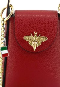 Rode leren handtas met een gouden bijmotief op de klep en een charm van de Italiaanse vlag. Inclusief een gouden ketting voor de schouderband.
