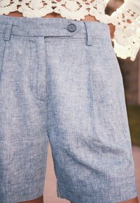 Lichtblauwe linnen shorts met een gestructureerde afwerking, voorzien van een ritssluiting aan de voorzijde, plooien en zijzakken.