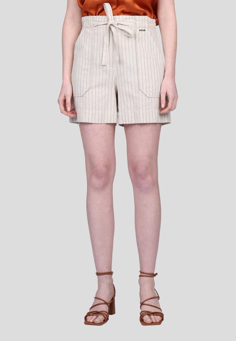Shorts rayés beiges avec une taille à cordon de serrage, poches avant et coupe décontractée. Ils sont associés à des sandales à talons broux à anses.