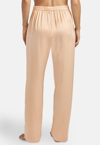 Pantalons larges couleur pêche clair en tissu lisse, avec une taille élastique et une coupe droite de la taille à l'ourlet.