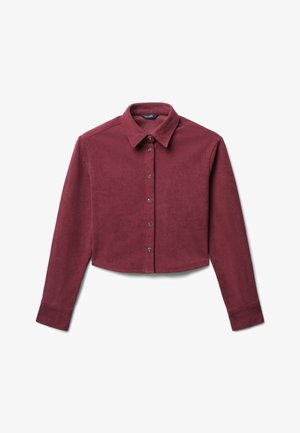 Cropped, maroon corduroy shirt with a button-up front, collar, and long sleeves. Features prominent ribbed texture and metallic buttons.
