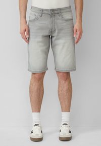 Pantaloni corti in denim grigio chiaro con texture sbiadita, cinque tasche e orlo arrotolato, abbinati a sneakers bianche e calzini bianchi.