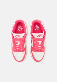 Nike sneakers med et pink og hvidt farveskema, der har en tekstureret overdel, perforeret tå og fremtrædende snørebånd. Accentueret logo på tungen.