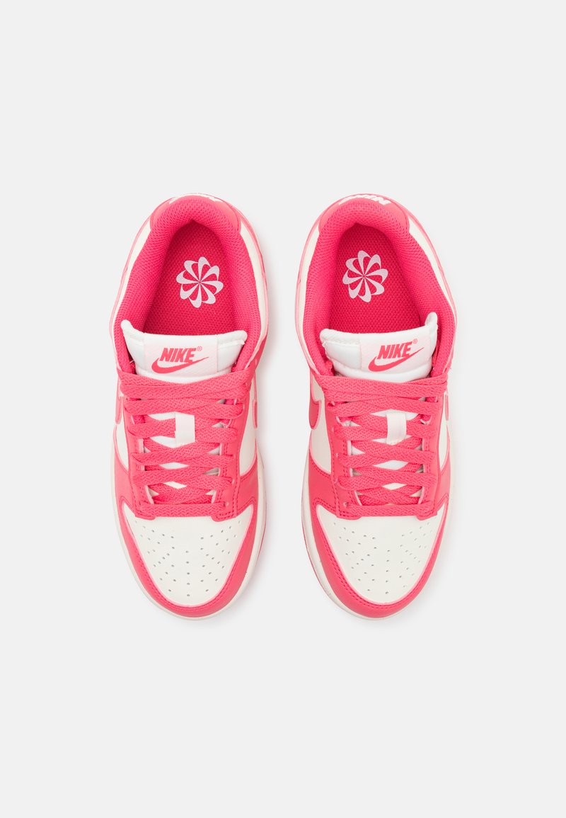 Nike Sneaker in einem pink-weißen Farbschema, mit einer strukturierten Oberfläche, perforierter Zehenpartie und auffälligen Schnürsenkeln. Akzentuiertes Logo auf der Zunge.