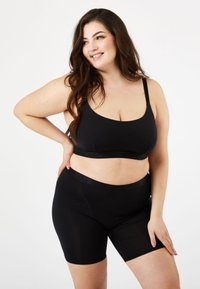 Musta croppi toppi ja siihen sopivat shortsit joustavaa kangasta. Tyylikäs muotoilu ohuilla olkaimilla ja joustovyötäröllä. Ei näkyviä kuvioita.