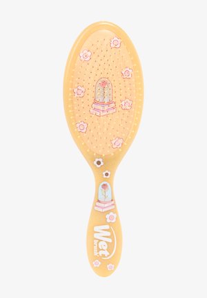 Brosse à cheveux Wet Brush jaune décorée de fleurs roses et une illustration d'une rose sous un dôme en verre sur des livres.