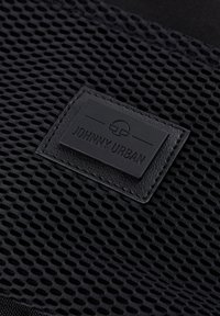 Black mesh fabric features with a textured surface, branded leather label reading "JOHNNY URBAN," sewn with black thread.