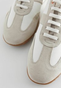 Hellgraue Wildledersneakers mit weißen Lederpaneelen, runder Zehenpartie und weißen Schnürsenkeln. Verfügt über eine Gummisohle und Nähdetails.