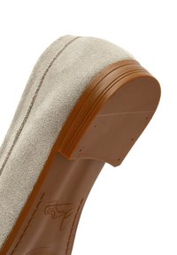 Scarpa in suede beige con punta rotonda, suola in gomma e tacco liscio color terra. I dettagli delle cuciture lungo il bordo superiore aggiungono texture.