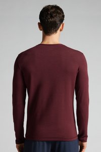 Langärmliges, Rundhals-Shirt aus tiefburgunder Stoff. Besitzt eine glatte Textur und eine figurbetonte Form mit minimalen Nähten.
