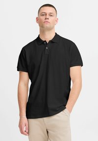 Sort polo skjorte lavet af bomuld, med en klassisk krave, korte ærmer og tre knapper med en glat tekstur.