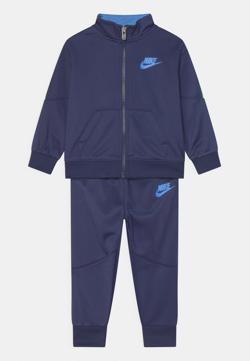 Chándal de Nike en azul marino que incluye una chaqueta con cremallera y cuello alto, y pantalones a juego, ambos fabricados en material sintético suave.
