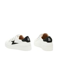 Baskets blanches avec une tige en cuir lisse, accent en daim noir au niveau du talon et logo en zigzag. Comprend une semelle en caoutchouc texturé et des lacets plats.