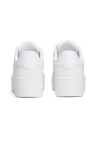 Bílé tenisky s hladkým svrškem z umělé kůže, polstrovaným límcem a texturovanou bílou gumovou podrážkou. Logo je vyražené na patě.