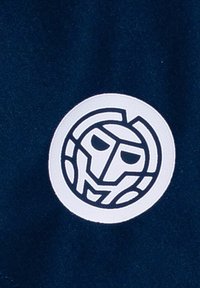 Parche circular blanco con un diseño de cara estilizada negra, cosido en una tela de color azul marino oscuro. El parche presenta líneas limpias y formas geométricas.