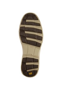 Suela de zapato con un patrón de goma marrón, con profundas ranuras, una plantilla beige y un logo amarillo de CAT cerca del talón.