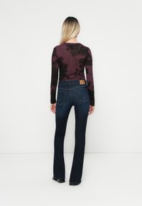 Donkerblauwe flared jeans van denim met een middelhoge taille. Heeft vijf zakken en een leren logo-label op de achterzijde van de tailleband.