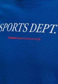 Blå bomullströja med fet vit text "SPORTS DEPT." och röd "hummel PERFORMANCE"-logotyp. Snygg struktur och rund halsringning.