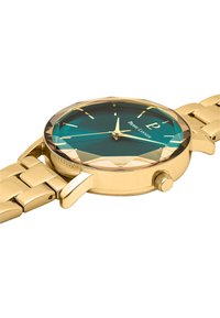Reloj de metal dorado con una esfera facetada en tonos azul-verde, marcadores de hora dorados y un brazalete de eslabones dorados a juego. Incluye una corona lateral.