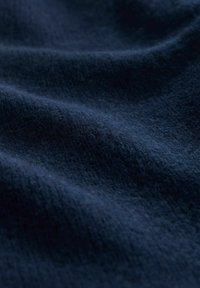 Dunkelblauer Stoff mit einer weichen, strukturierten Oberfläche, die sanfte Falten und ein leicht flauschiges Finish zeigt, ideal für Polsterungen oder Kleidung.
