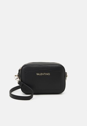 Petit sac bracelet en cuir noir Valentino avec logo doré à l'avant et bandoulière amovible sur fond blanc.