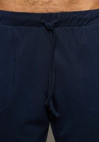 Námořnické modré tepláky s elastickým pasem, se stahovací šňůrkou a dvěma předními kapsami, vyrobené z měkké, prodyšné látky.