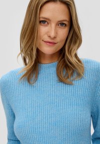 Hellblaues Strickpullover mit hohem Kragen, strukturiertem Muster und langen Ärmeln. Weicher Stoff mit figurbetontem Schnitt.
