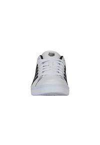 Fehér bőr sneaker fekete csíkokkal és kerek orral; lapos fehér fűzőkkel és logóval a nyelvén. Erősített gumi talp.