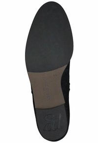 Suela de zapato de ante negra con un exterior de goma texturizada, presenta un insertado en tono marrón claro y un logo en relieve. Tamaño marcado como 4½. Diseño plano.