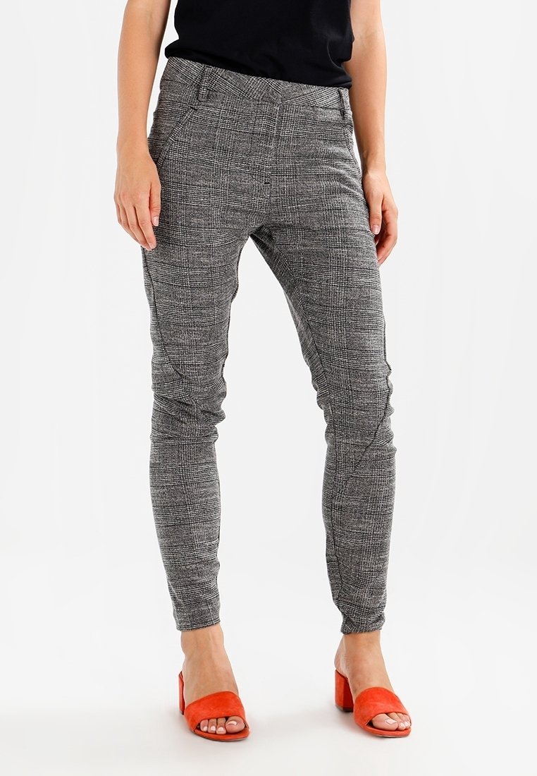 Pantalon gris à carreaux coupe slim, tissu texturé, taille mi-haute, détails subtilement cousus, associé à des sandales rouges à talons blocs.